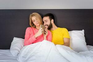 Young Sweet Couple at Bed Watching Something on Tablet Gadget photo