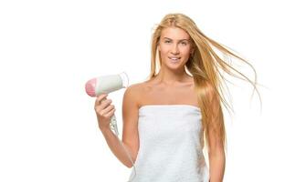 Young woman in towel dries hair a hairdryer photo