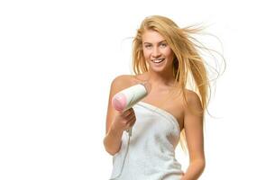 joven mujer en toalla se seca pelo un secador de pelo foto