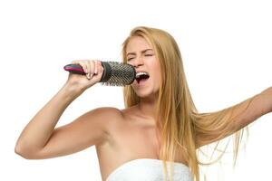 Happy woman in towel singing using comb photo