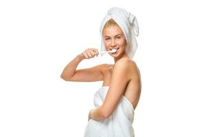 Young attractive woman blue eyes in towel brushing her teeth photo