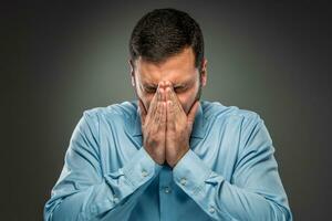 Portrait of upset man covering his face by hands photo