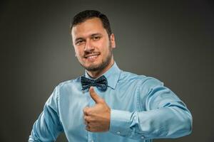 Smiling young man making the ok thumbs up hand sign photo