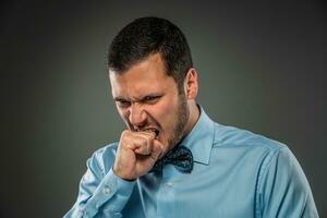 Portrait of an angry guy biting his fist. Human emotion. photo