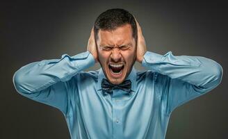 Portrait angry upset young man in blue shirt, butterfly tie photo