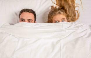 Young lovely couple lying in a bed, looking at camera photo