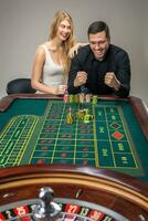 Man and woman cheering at roulette table in casino photo