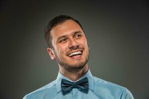 Smiling young man in blue shirt and butterfly tie photo