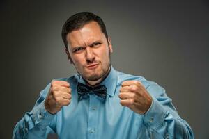 Portrait angry upset young man in blue shirt, butterfly tie photo