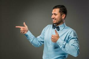 Smiling man pointing to something with an index finger photo