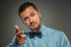 Smiling man is gesturing with hand, pointing finger at camera photo