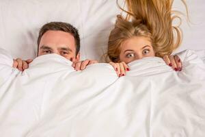 Young lovely couple lying in a bed, looking at camera photo