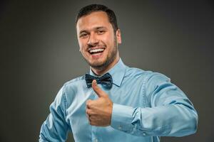 Smiling young man making the ok thumbs up hand sign photo