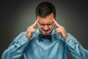 Portrait angry upset young man in blue shirt, butterfly tie photo