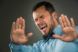 retrato enojado trastornado joven hombre en azul camisa, mariposa Corbata foto