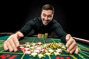 Young handsome man playing roulette wins at the casino photo