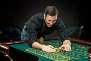 joven hermoso hombre jugando ruleta gana a el casino foto