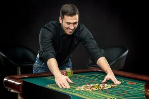 Young handsome man playing roulette wins at the casino photo