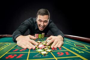 Young handsome man playing roulette wins at the casino photo