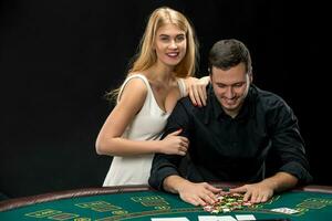 Young couple playing poker. Man taking poker chips after winning photo