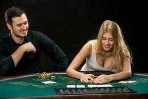 Young couple playing poker, woman taking poker chips after winning photo