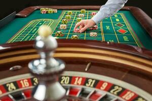 Roulette and piles of gambling chips on a green table. photo