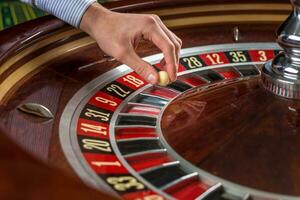 Roulette wheel and croupier hand with white ball in casino photo