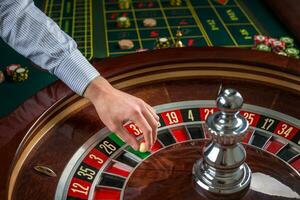 Roulette wheel and croupier hand with white ball in casino photo