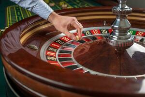 Roulette wheel and croupier hand with white ball in casino photo