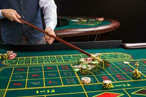 croupier collects chips using stick in casino. photo