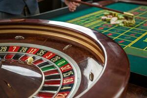 Roulette and piles of gambling chips on a green table. photo