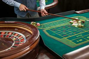 Roulette and piles of gambling chips on a green table. photo