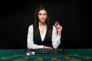 The beautiful girl, dealer, behind a table for poker photo