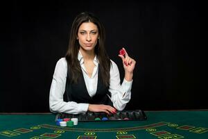 The beautiful girl, dealer, behind a table for poker photo