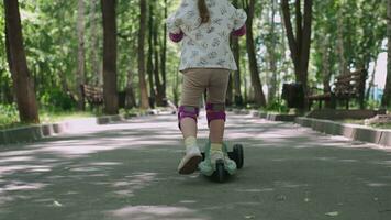 mãe ensina filha para passeio uma lambreta dentro a parque dentro verão. video