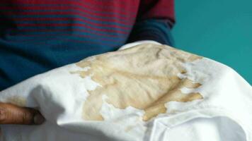 men holding white color dirty shirt, showing making stain video