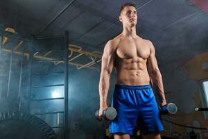 Man doing heavy weight exercise with dumbbells in gym photo