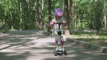 Girl 3 years old rides a scooter in protective clothing video