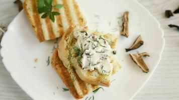 fried bread toast with cheese spread with boiled dried mushrooms on a wooden table. video