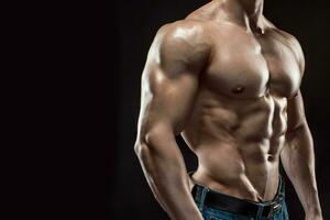 Muscular bodybuilder guy doing posing over black background photo