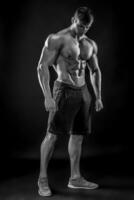 Muscular bodybuilder guy doing posing over black background photo