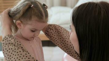 Mom prepares her daughter for a birthday celebration by fixing her hair. Daughter hugs mom. video