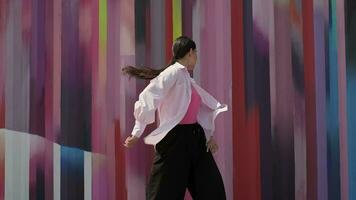 Energetic cheerful girl dancing on the background of a colored wall video