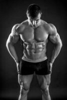 Muscular bodybuilder guy doing posing over black background photo