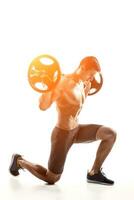 Muscular man standing on knee, holding barbell over his head photo