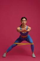 Girl doing lateral lunges with resistance band on maroon background photo