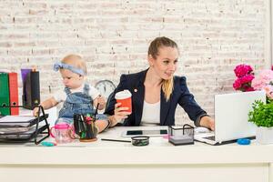 mamá y mujer de negocios trabajando con ordenador portátil computadora a hogar y jugando con su bebé muchacha. foto