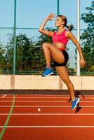 joven, hermosa niña atleta en ropa de deporte haciendo calentar a el estadio foto