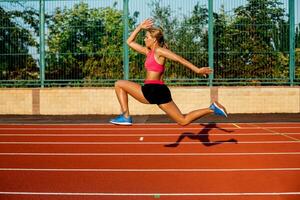 lado ver hermosa joven mujer ejercicio trotar y corriendo en atlético pista en estadio foto