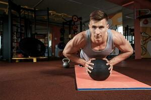 atractivo masculino atleta ejecutando Lagartijas en medicina pelota foto